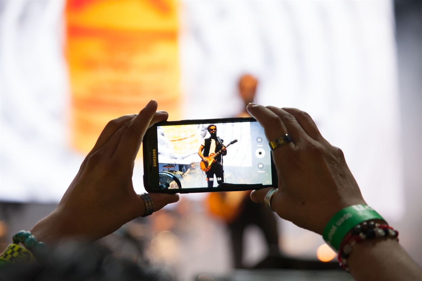 Audience member filming a Molotov guitarist performing live on stage using a smartphone.