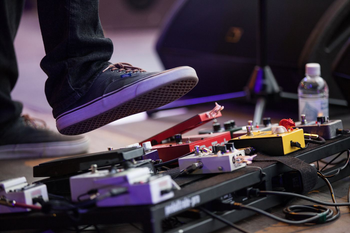 Close-up of a guitar pedalboard used during a live concert performance.